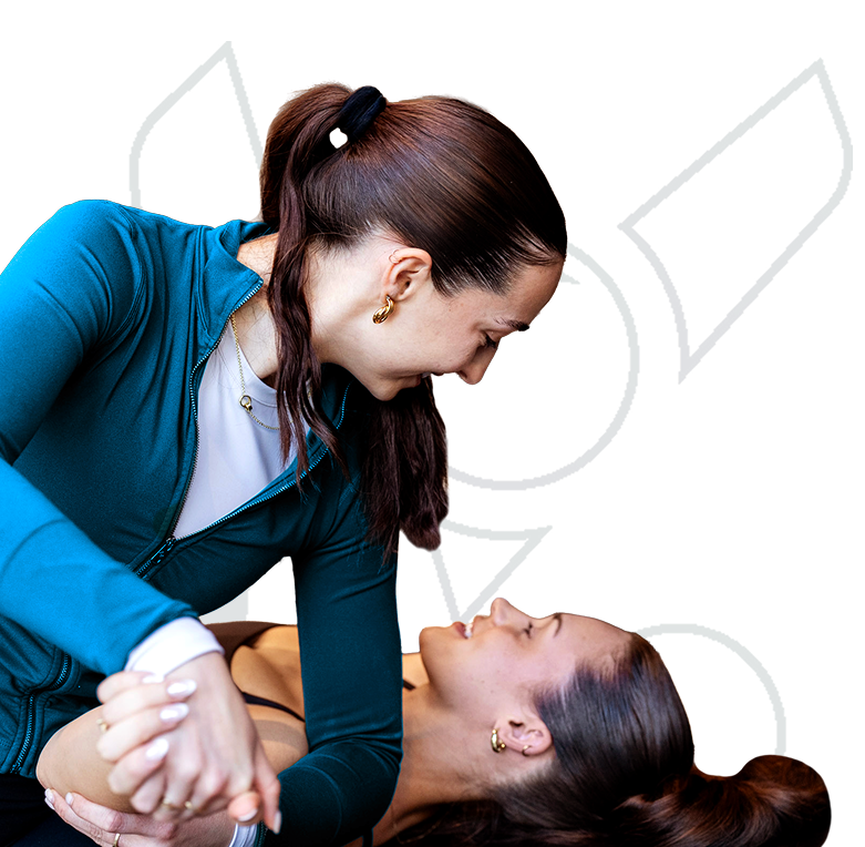Physical therapist assisting a patient with a supported stretch or mobility exercise while the patient lies on the treatment table.